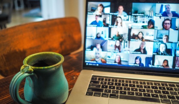 zoom call on laptop screen, with a blue mug next to it on the desk.
