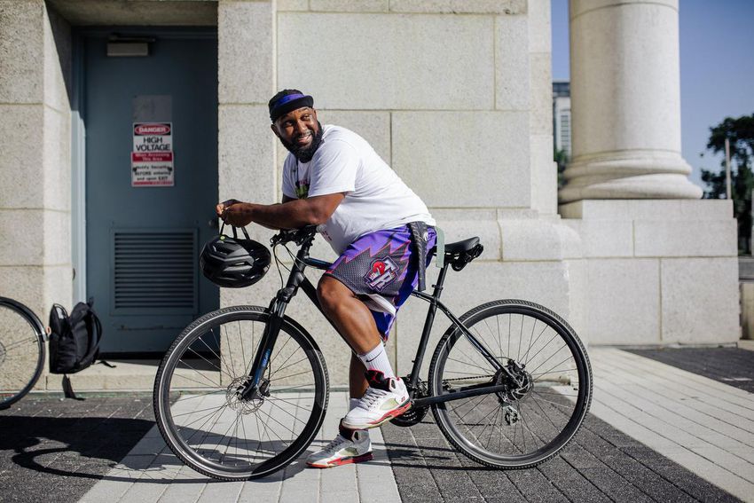 Christopher McGarrell on a parked bicycle, leaning forward and looking over his shoulder