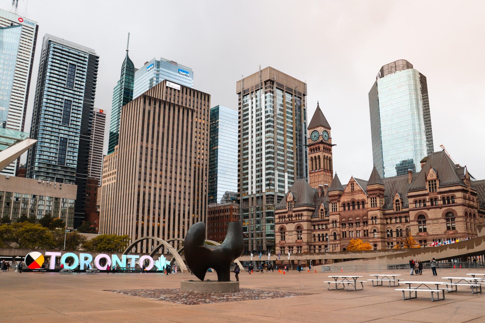A sign with colourful letters and tall buildings outdoors