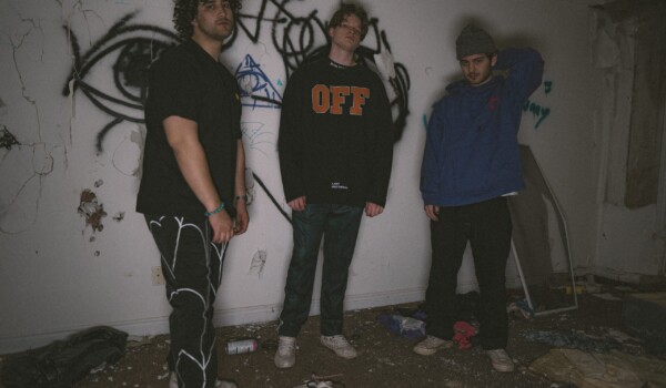 Members of Bloom Media standing in front of a graffitied white wall