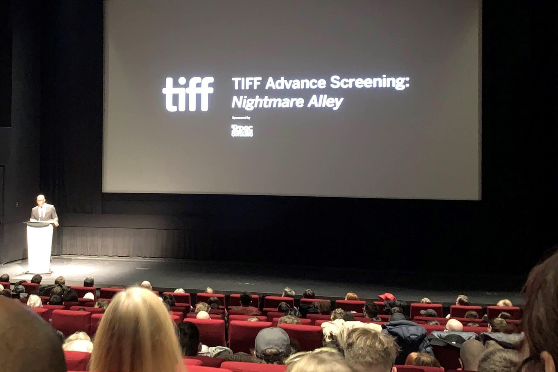 A black screen with white text on it in a movie theatre.